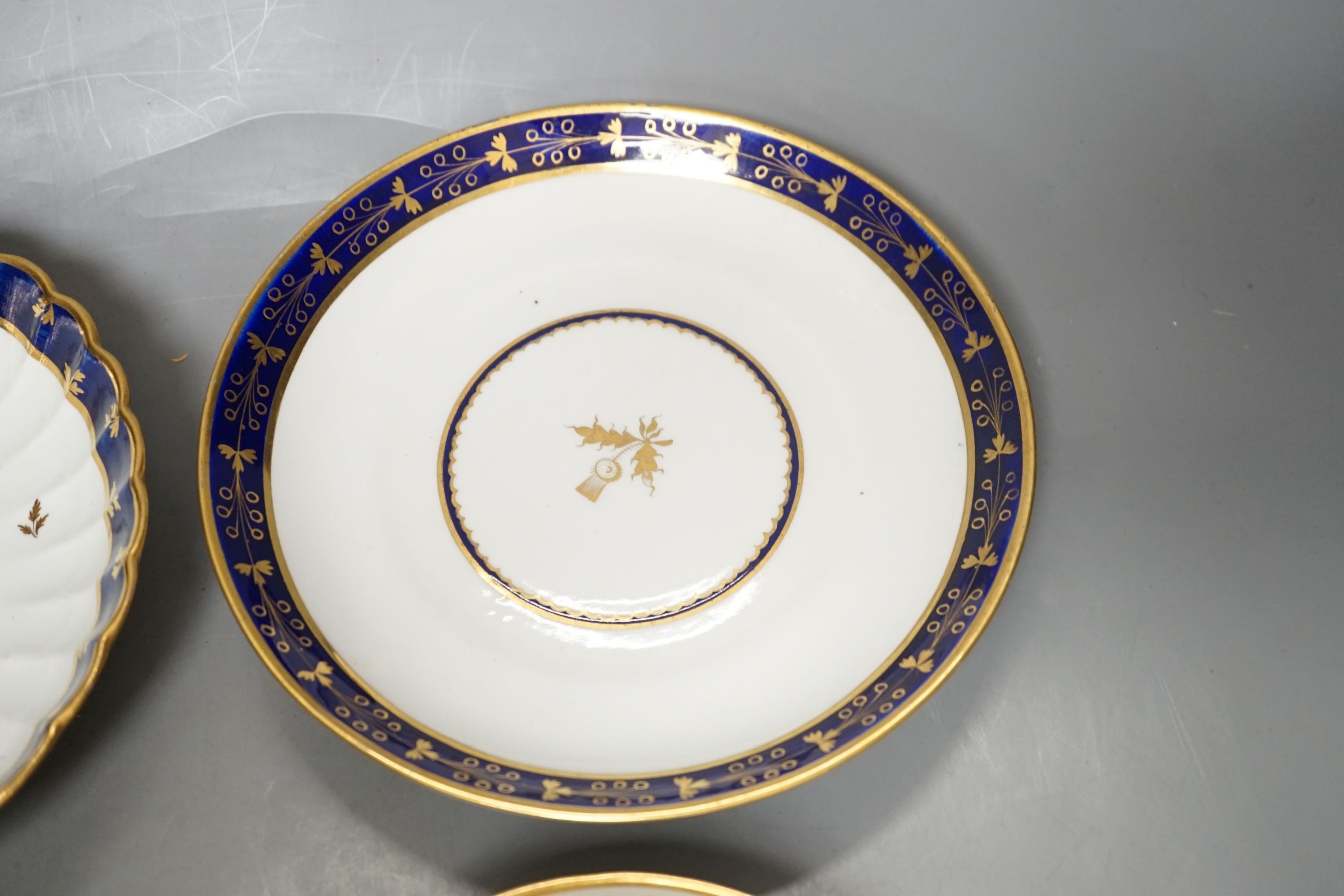 A Flight Barr and Barr teacup and saucer printed with shells, similar teacup and saucer with blue and gold decoration, and two Flight Barr and Barr gold and blue saucers dishes c. 1820, dish 20 cms diameter.